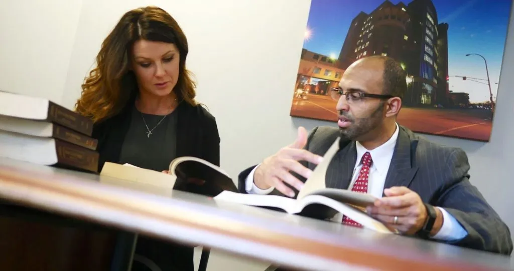 A man and a woman sitting together, reading books and talking.