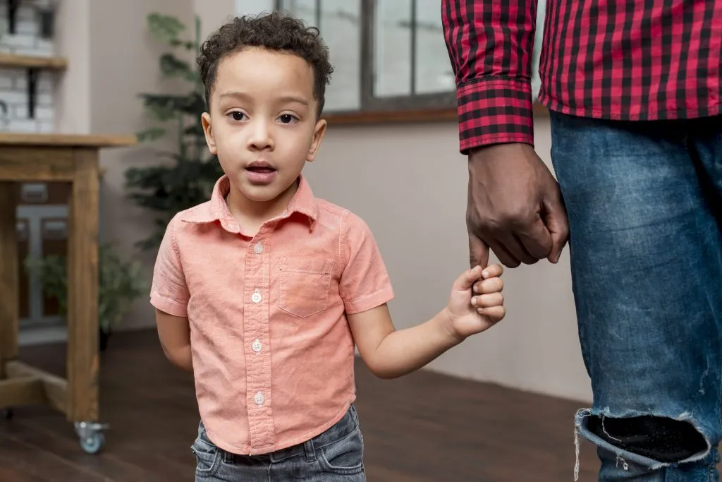 An image of a Black son holding his father’s hand.