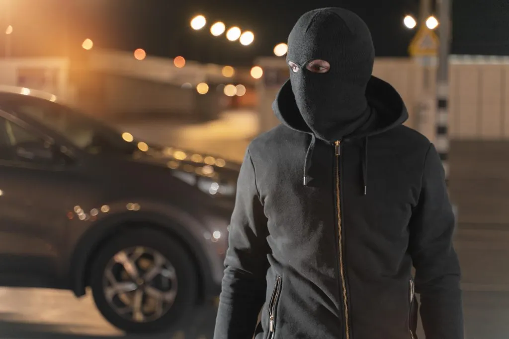 A close-up image of a man attempting to break into a car.