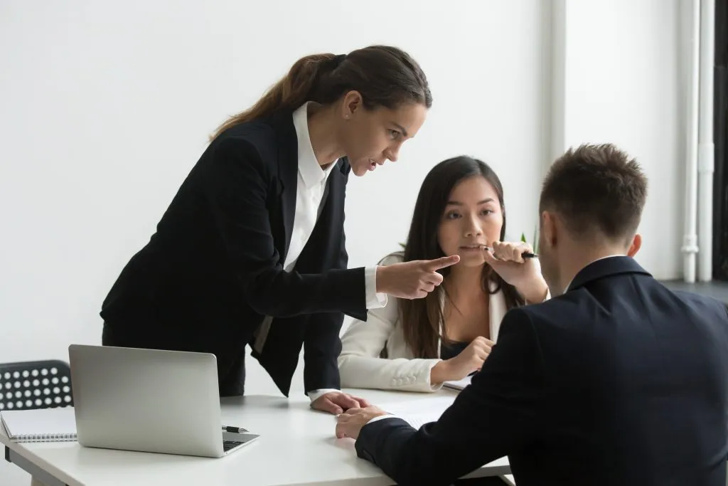 An image of a dissatisfied female executive scolding or reprimanding two colleagues.