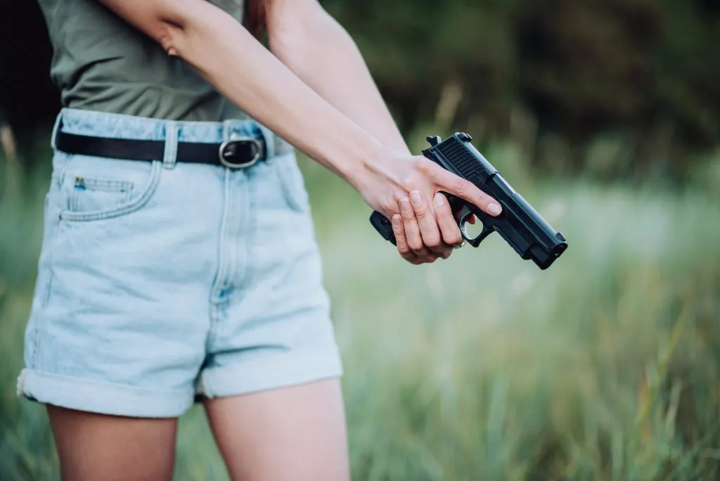An image of a girl wearing denim short with gun on her hand