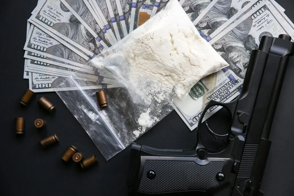 An image of a gun, bullet, money and a powder on the table