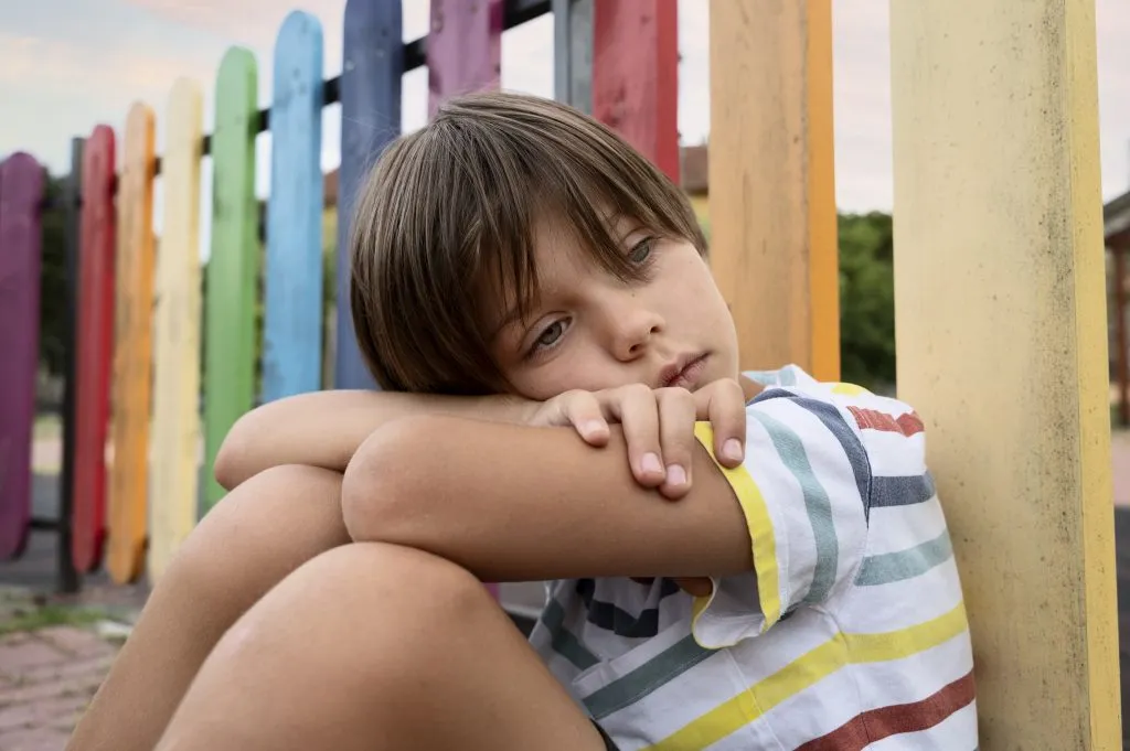 An image of a sad boy sitting alone on a park