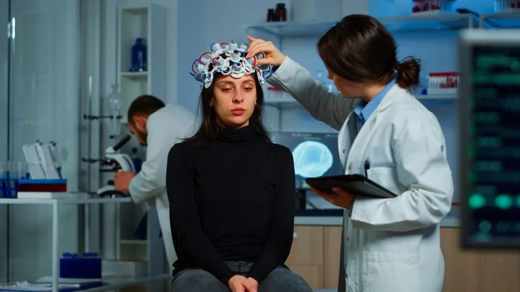 An image of a doctor with her patient putting something on her head to make some test
