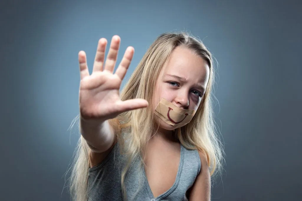 n image of a young girl with her mouth covered and her hand held open.