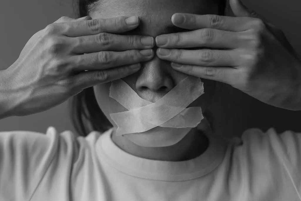 An image of a woman with mouth sealed and eyes close with the two hands