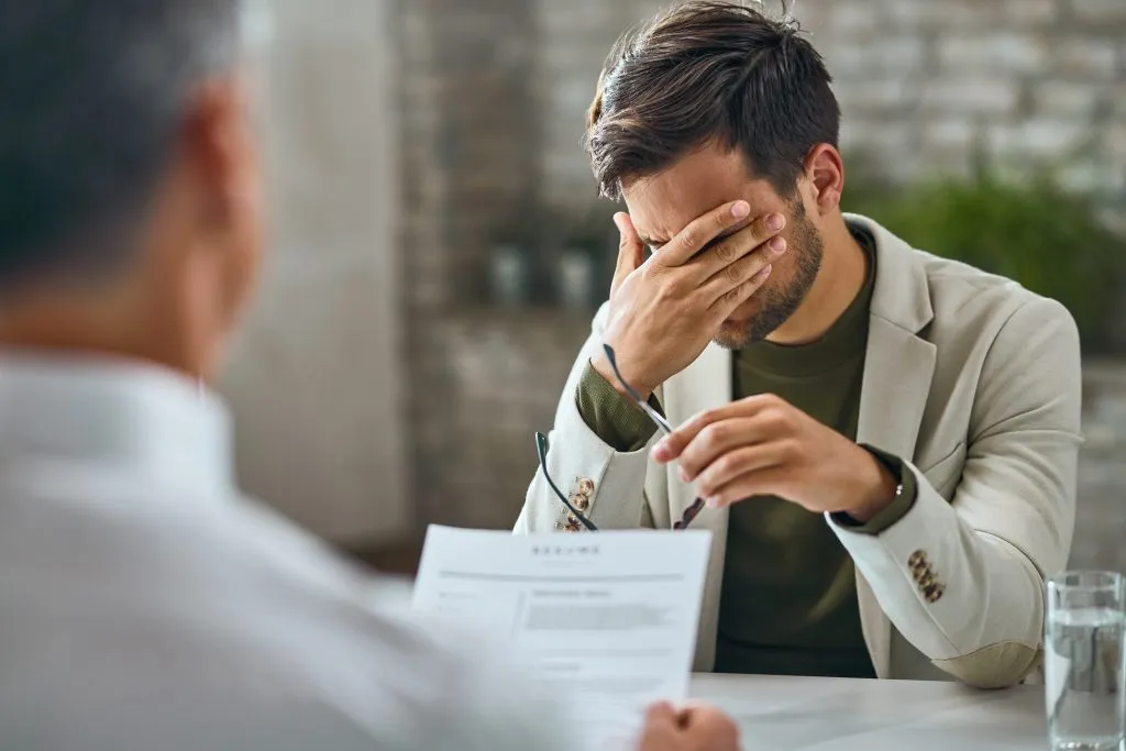 An image of a man with a troubled expression on his face in front of the interviewer.